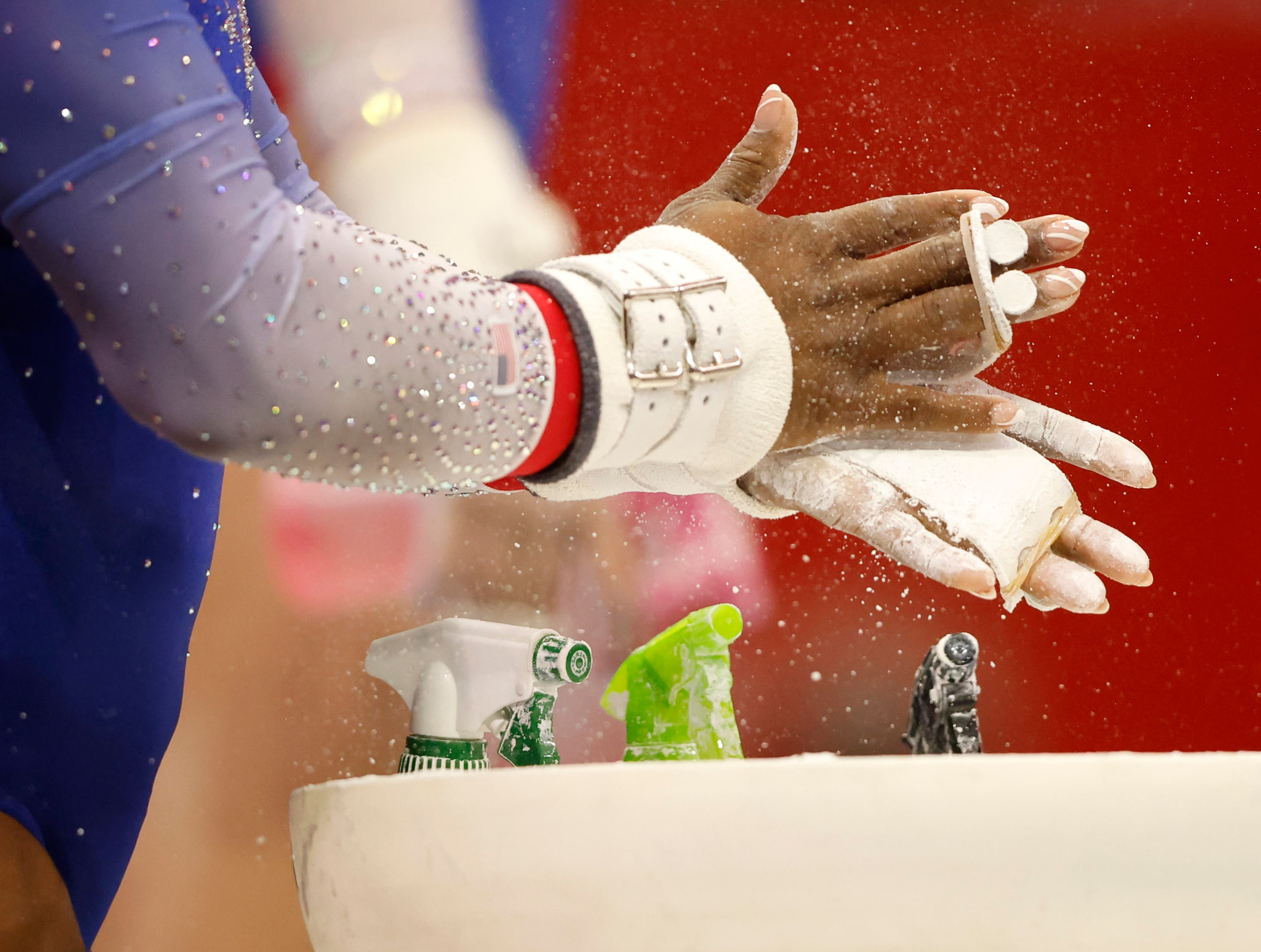 Simone Biles of World Champions uses chalk as she prepares to compete in the uneven bars...