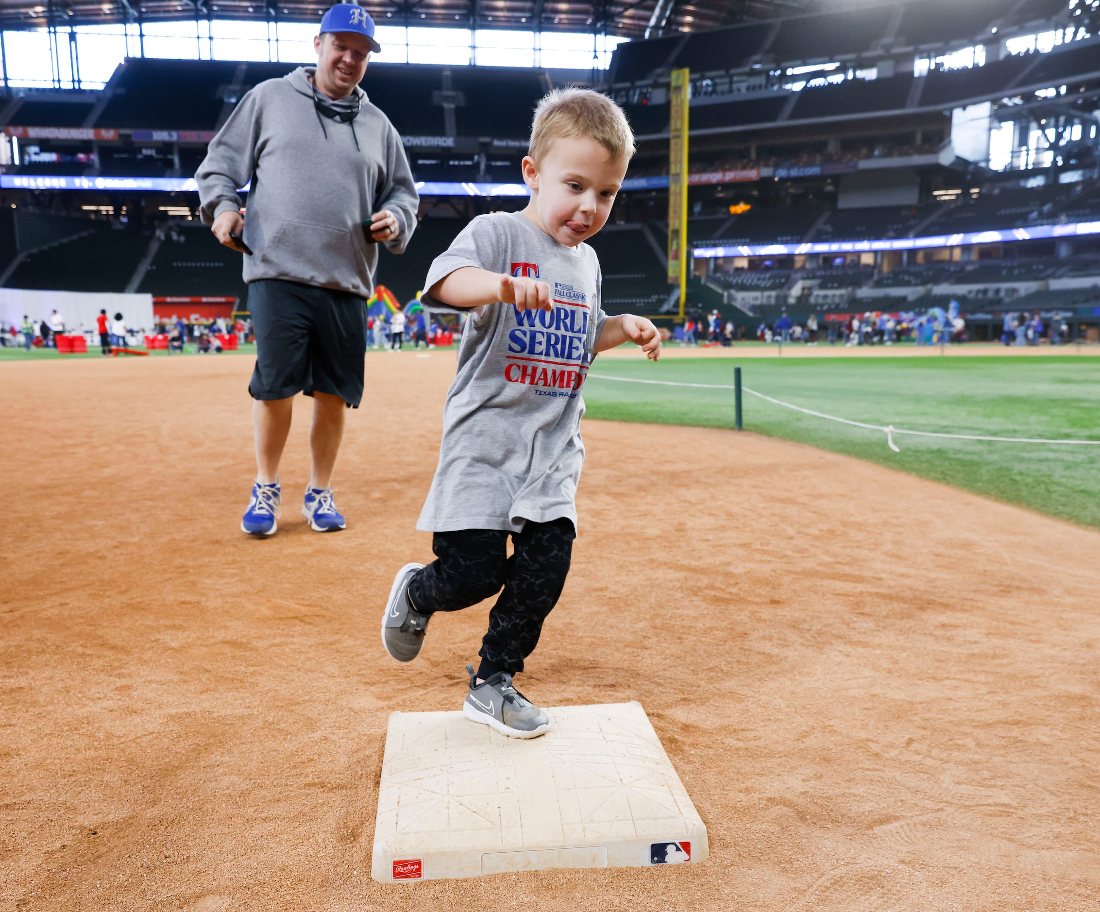 Kyle Clark (back), follows his son Rhett, 4, as he touches the third bases in between...