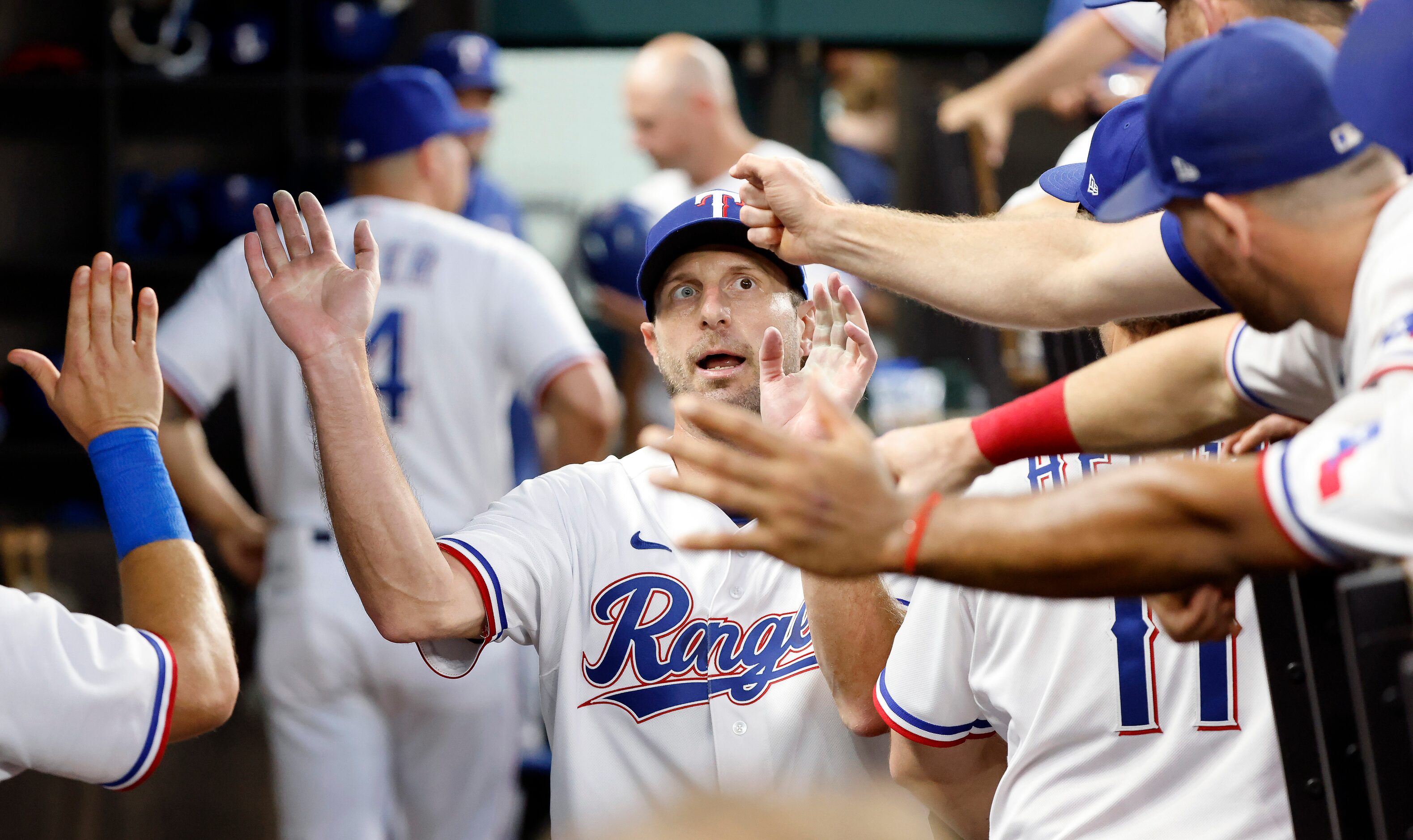 Texas Rangers starting pitcher Max Scherzer (31) delivers and receives fist bumps and...