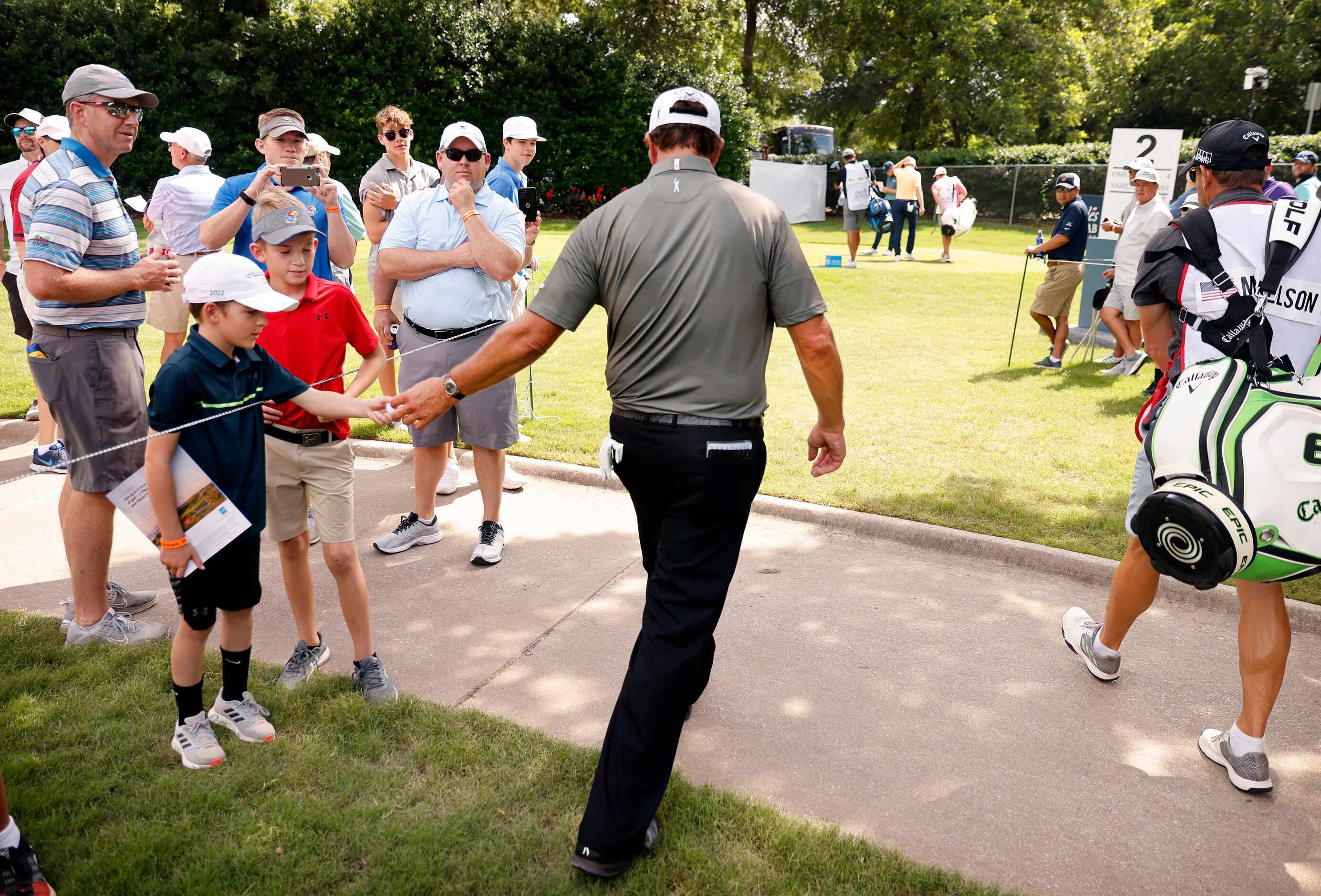 Professional golfer Phil Mickelson hands his ball to a young fan after making par on No. 1...