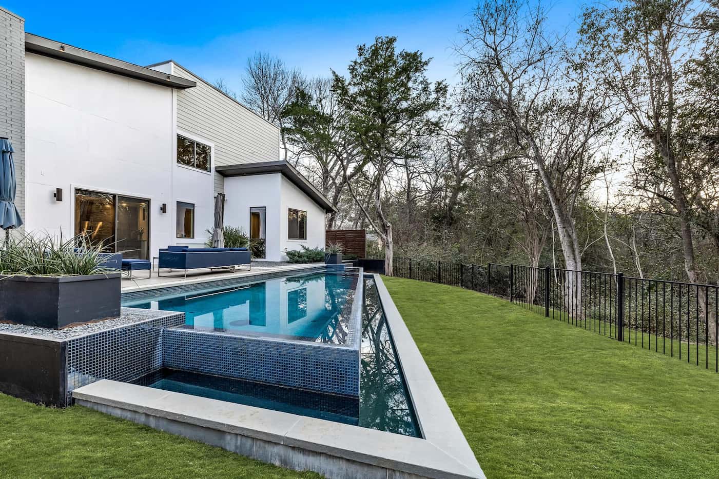 A heated infinity-edge pool looks out to the lush landscaping and wooded creek.