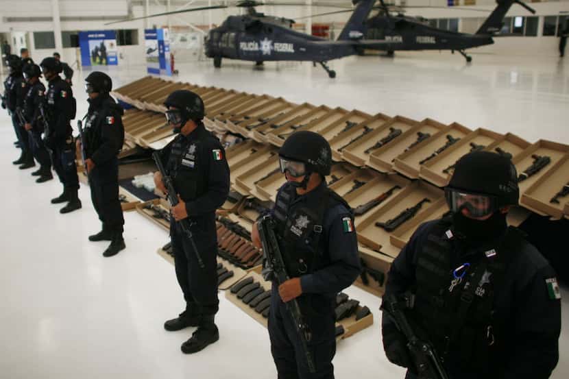  Federal police officers in Mexico City stand guard as seized weapons are shown to the media...