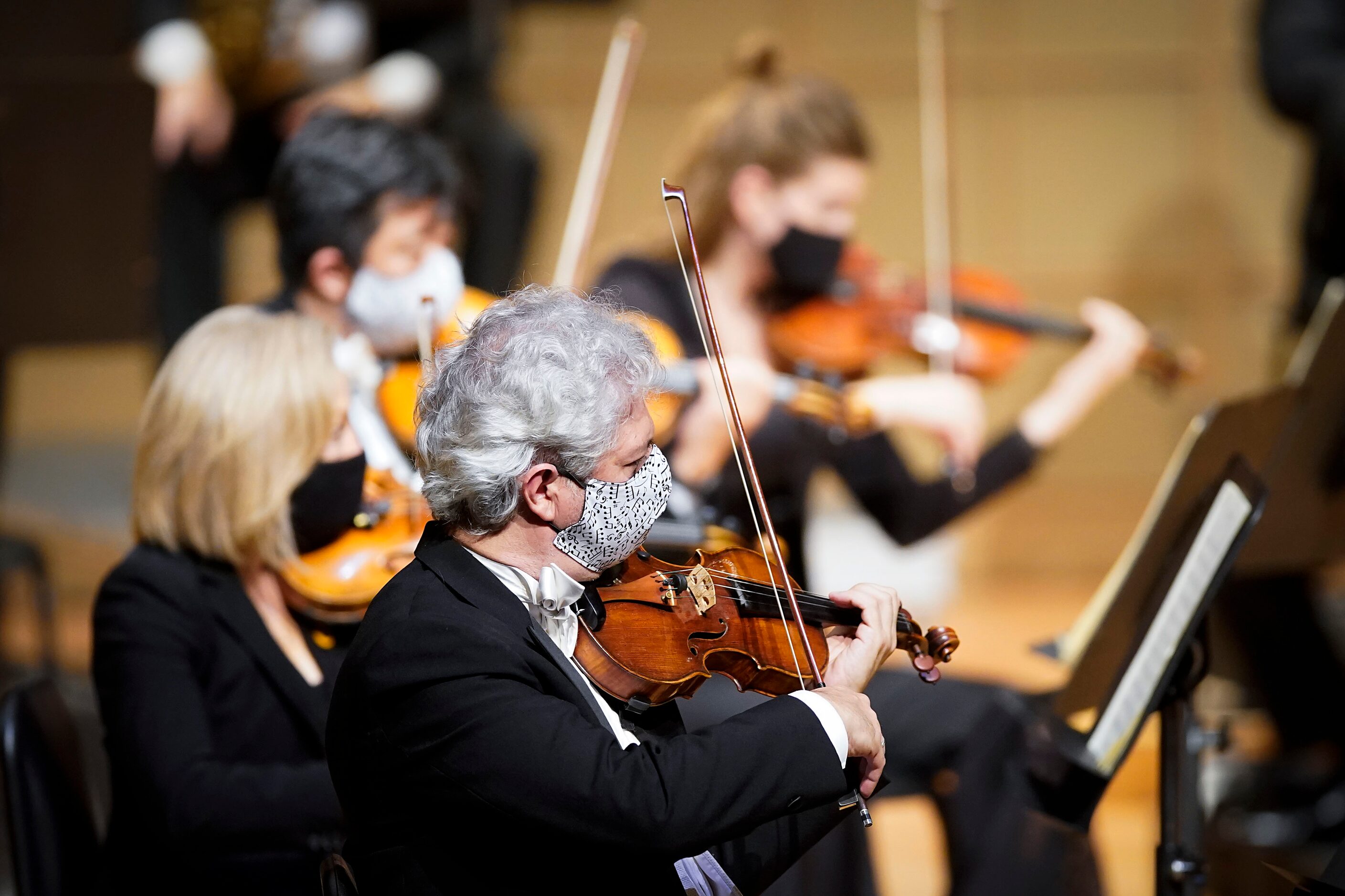 String players wear face masks as they perform during the season-opening Dallas Symphony...