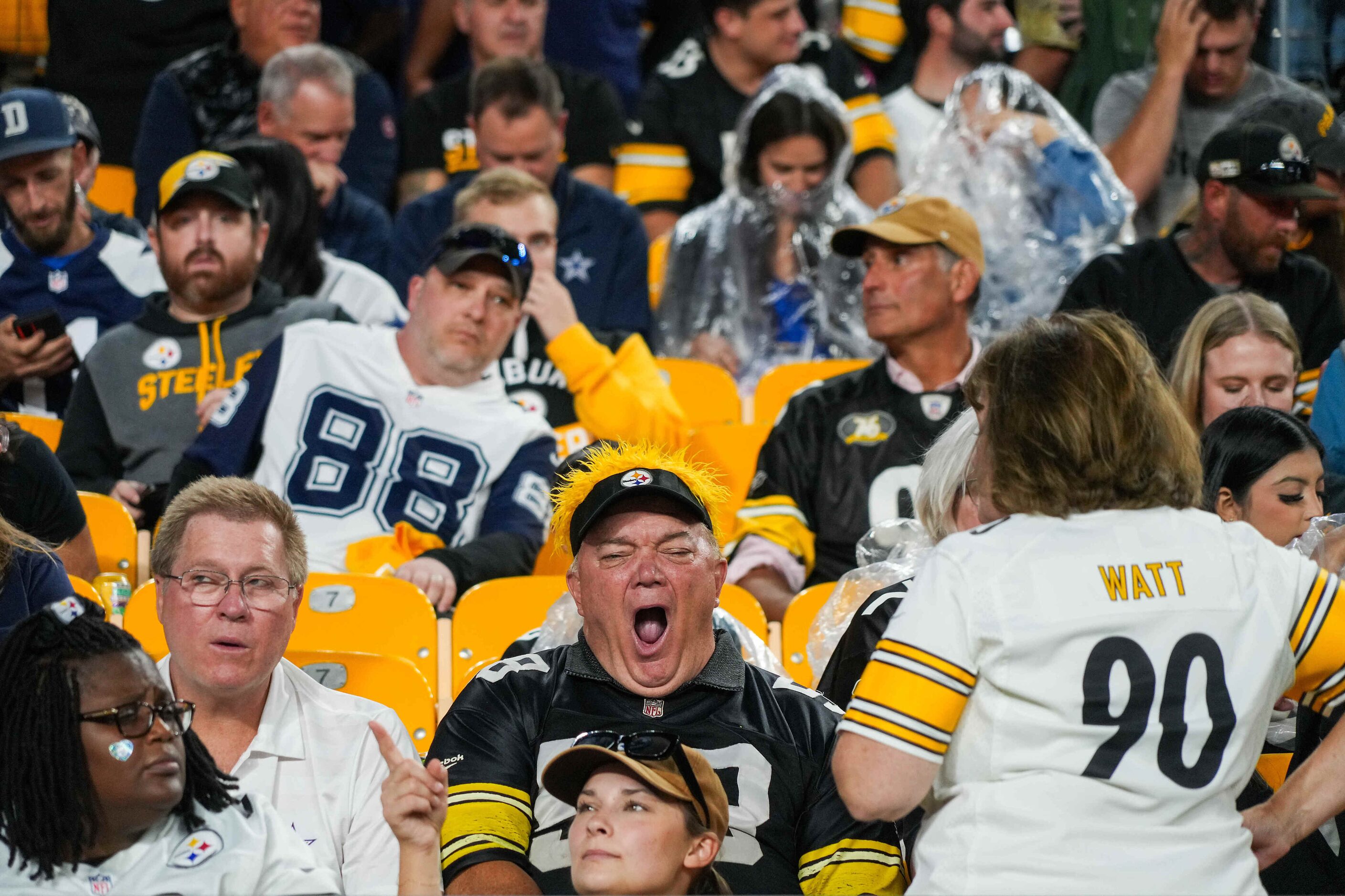 A fan yawns as others don rain ponchos during a weather delay before an NFL football game...