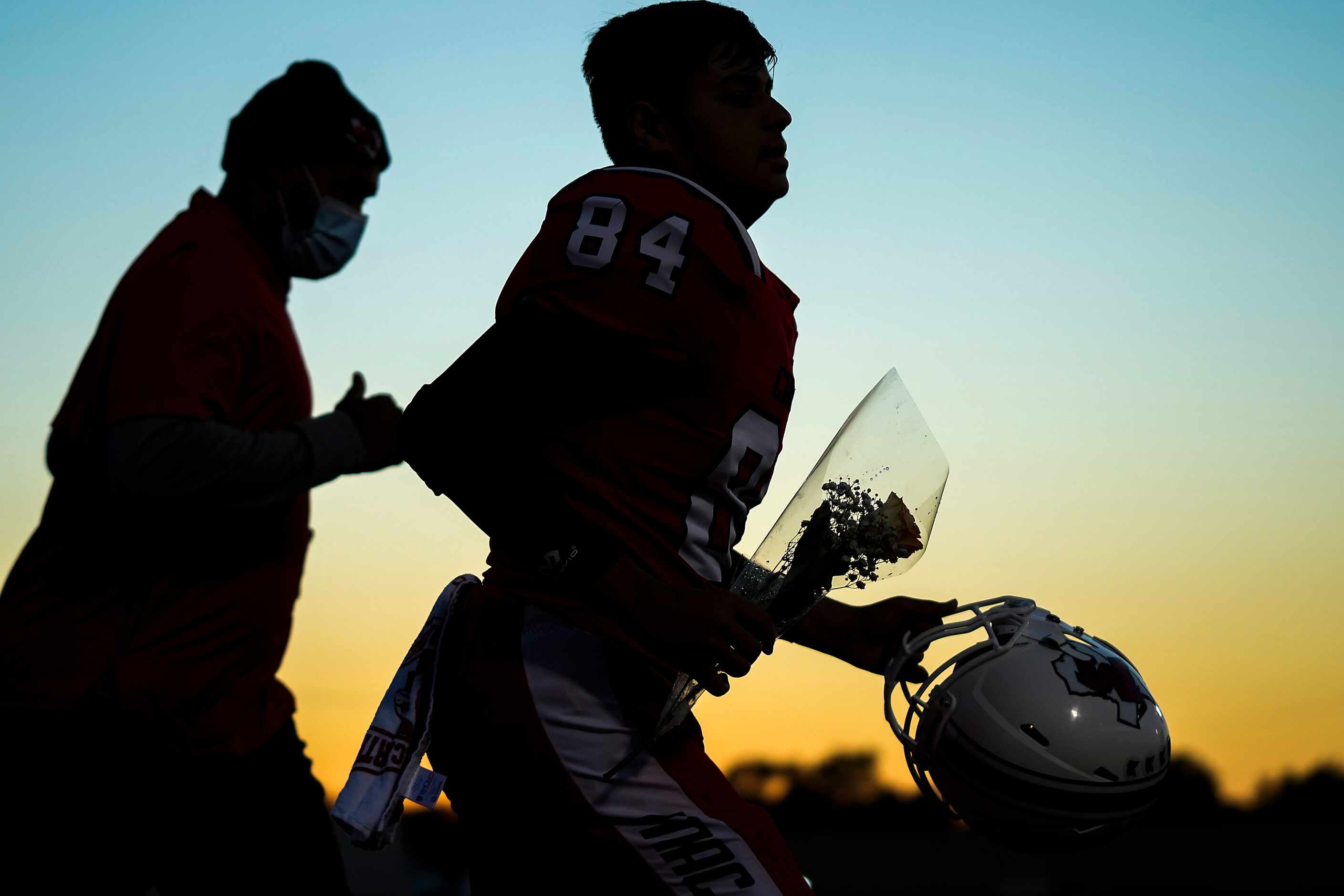 Irving MacArthur’s Nipun Gaind (84) carries flowers as he takes the field for senior day...