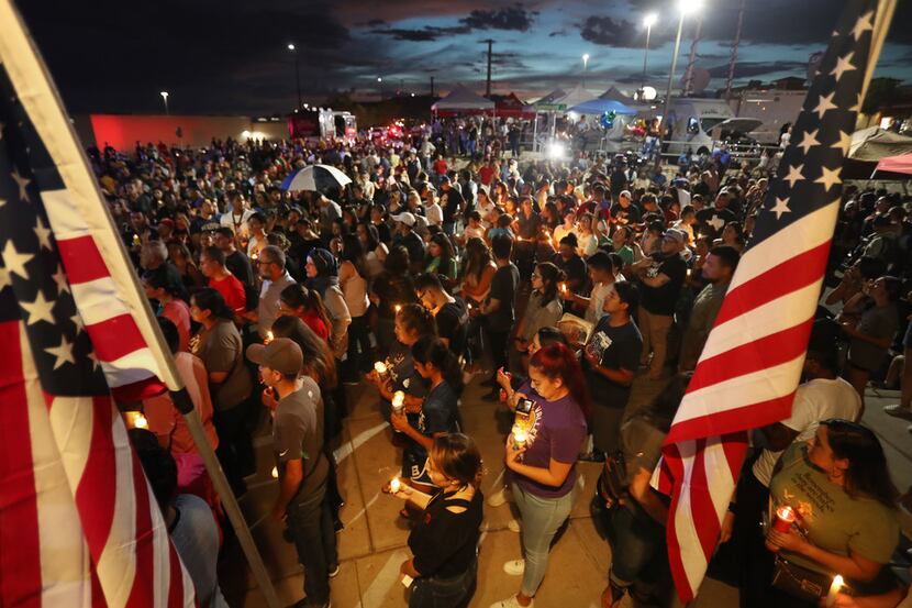 People attend a candlelight vigil on Aug. 7 at a makeshift memorial honoring victims of a...