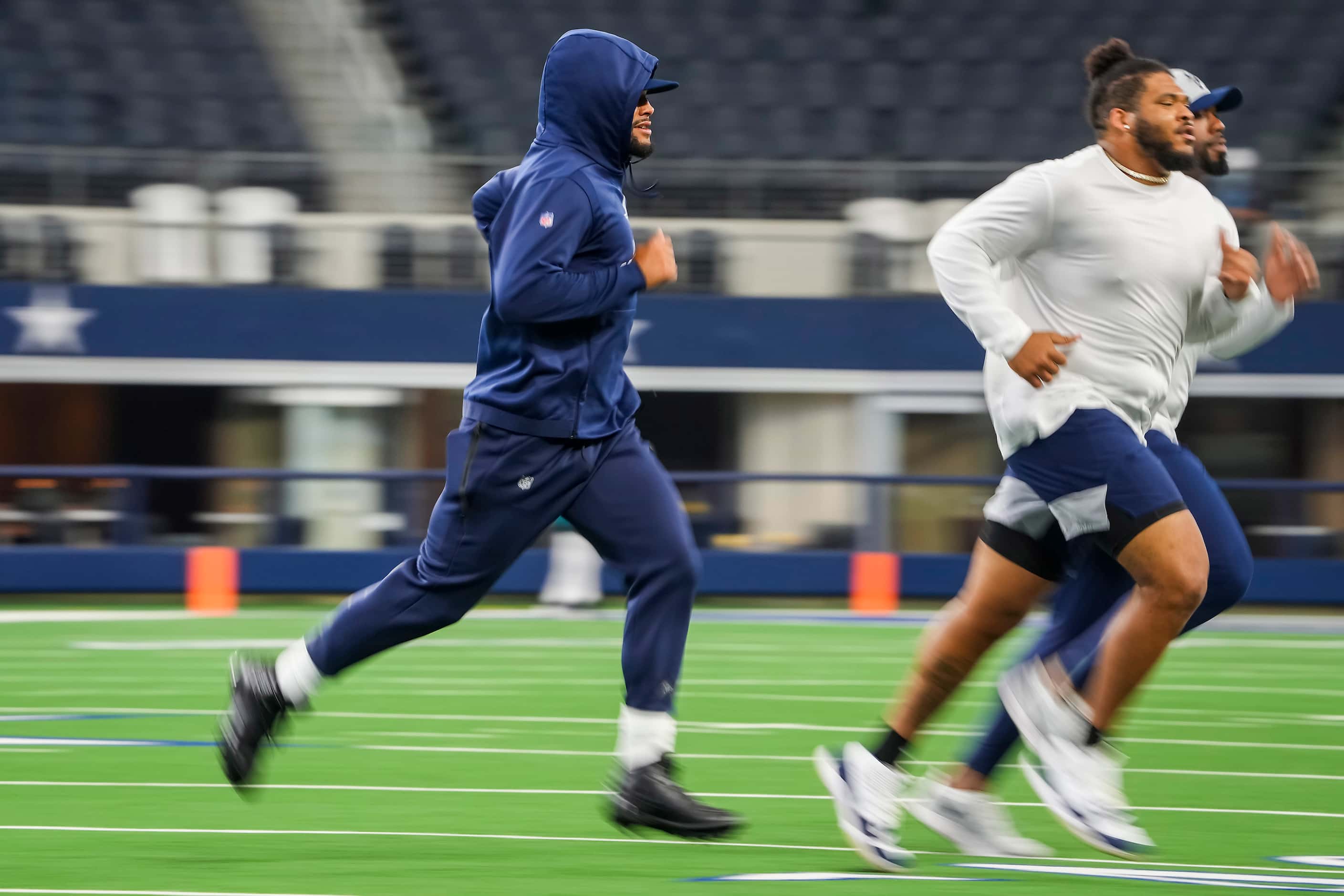 Dallas Cowboys quarterback Dak Prescott (left) runs on the field as players warm up before a...