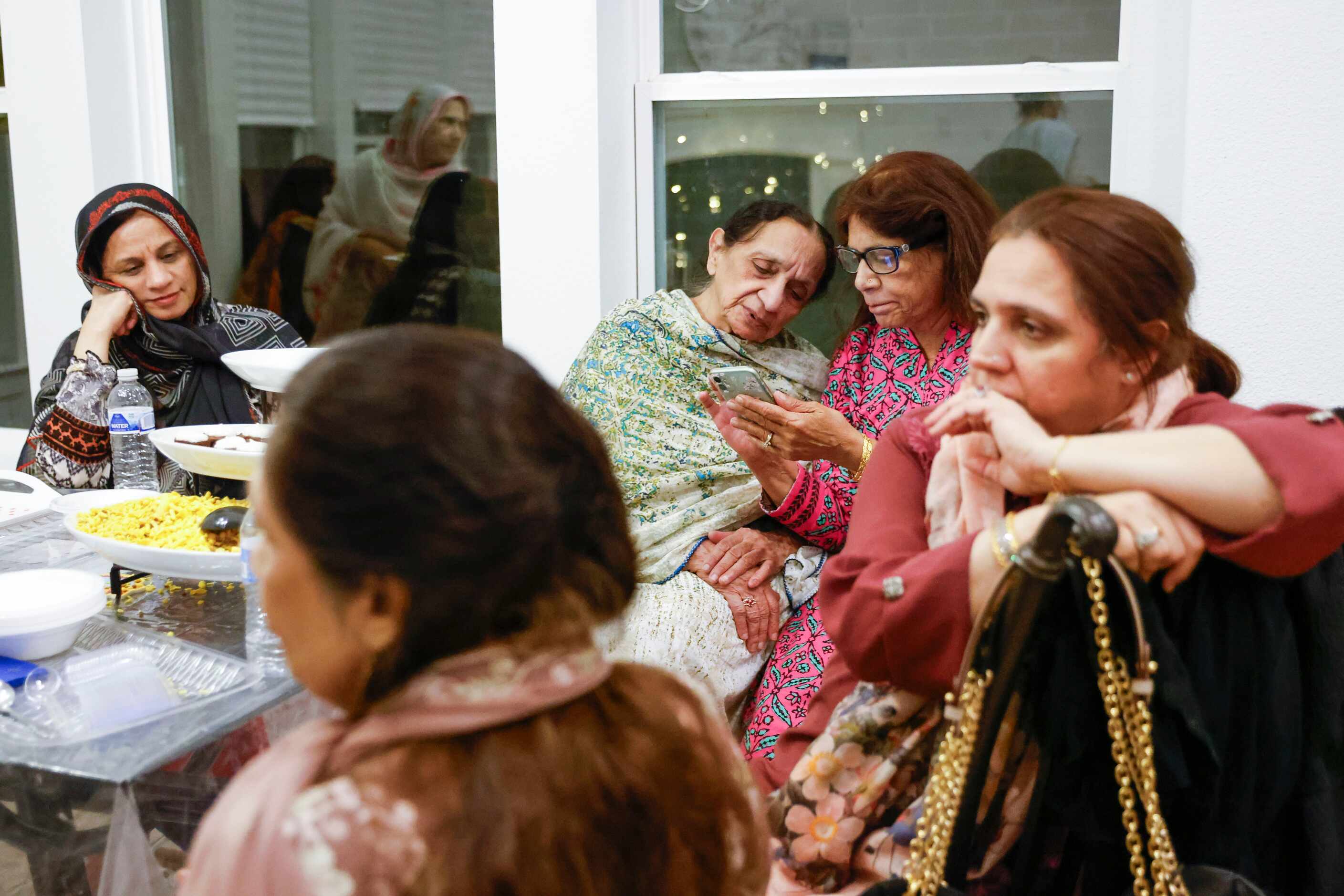Navin Butt, (back right), interacts with family friend Kulsum Ibrahim (back left), at the...