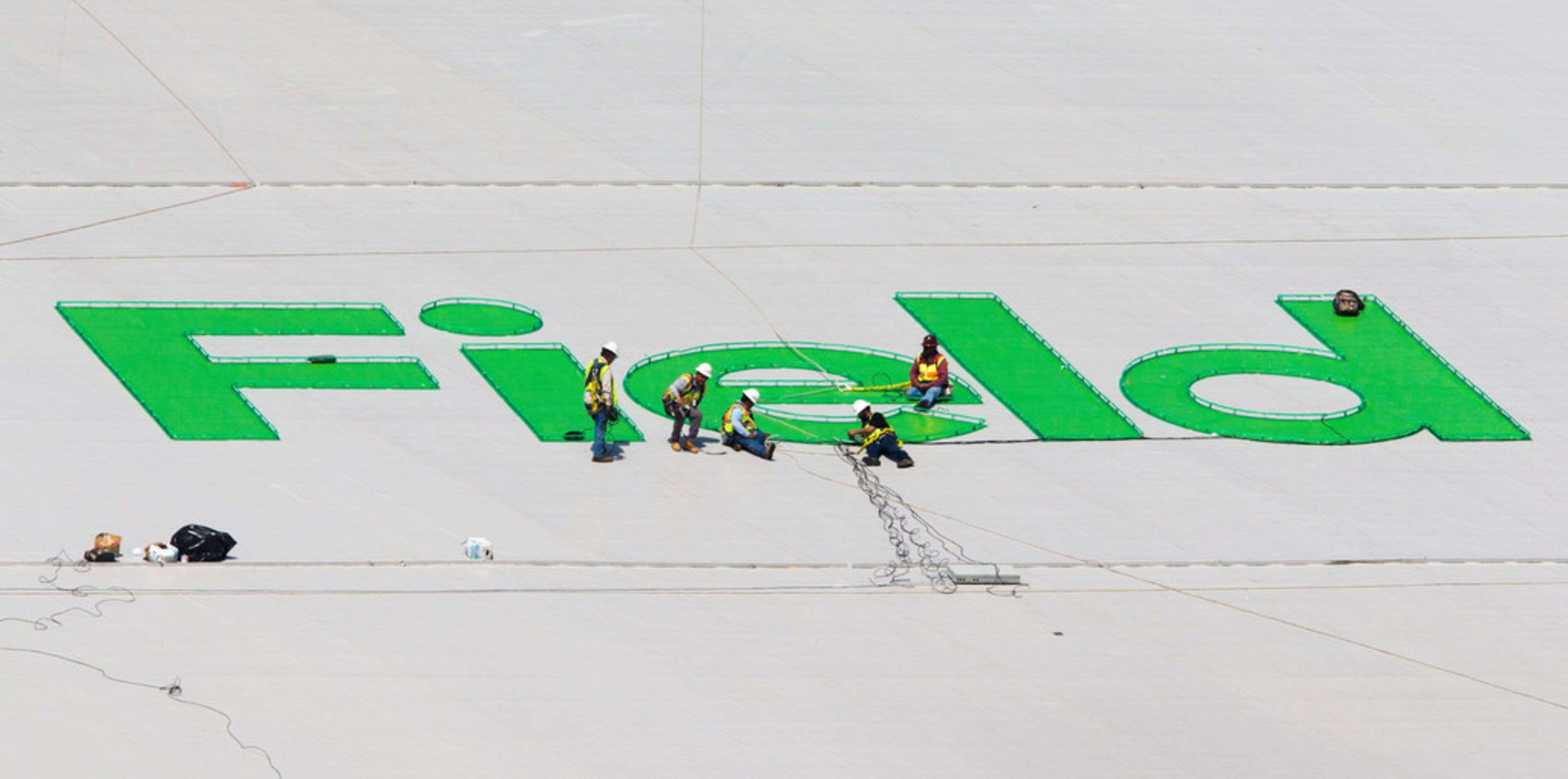 Crews work on a Globe Life Field logo on the roof of the stadium during an open house for...