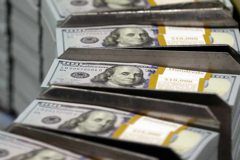 In this Sept. 24, 2013, file photo, just cut stacks of $100 bills make their way down the...