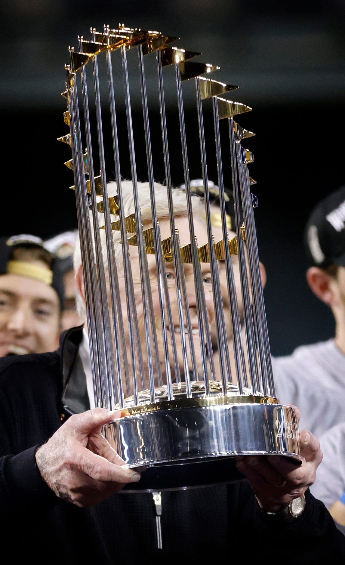 Texas Rangers co-owner Ray Davis is handed the World Series trophy during a post game...