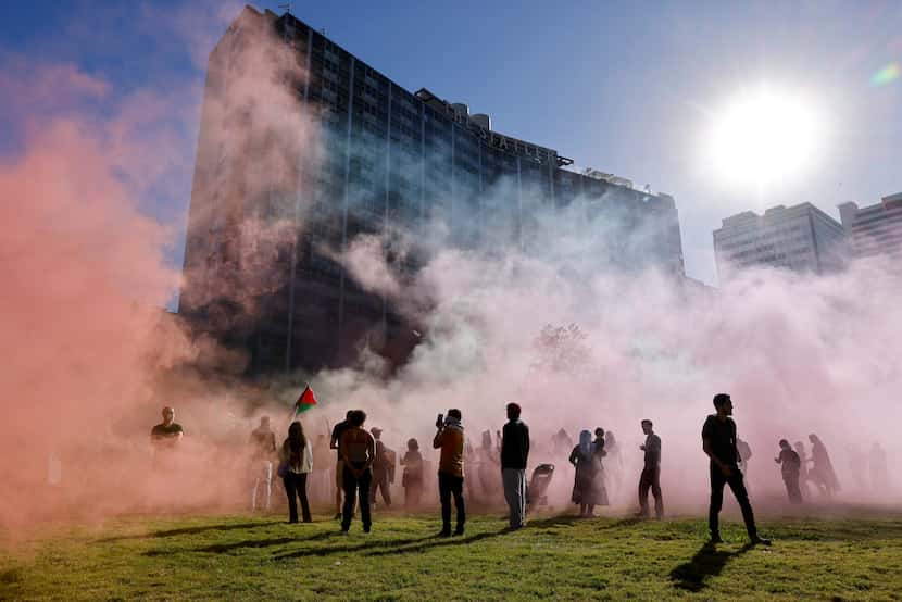 Colored smoke bombs set off by protesters fill the air during a protest organized by the The...