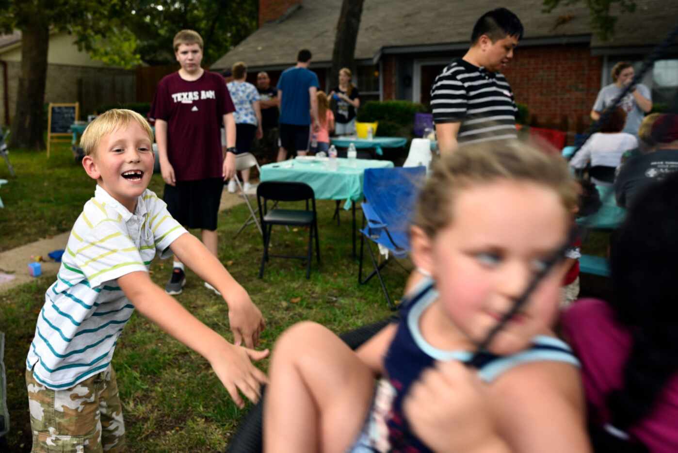 Luke Raleigh, 7, pushes a group of kids on a swing during Laura Daulton's turquoise table...