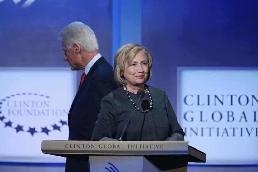 Former Secretary of State Hillary Clinton (R) stands at the podium as former U.S. President...
