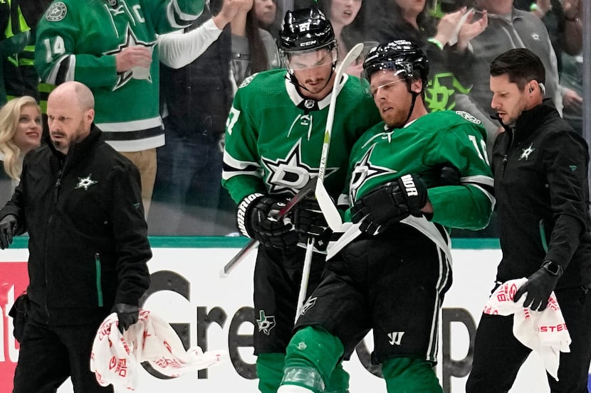 Dallas Stars' Joe Pavelski, second from right, is helped off the ice by Mason Marchment and...
