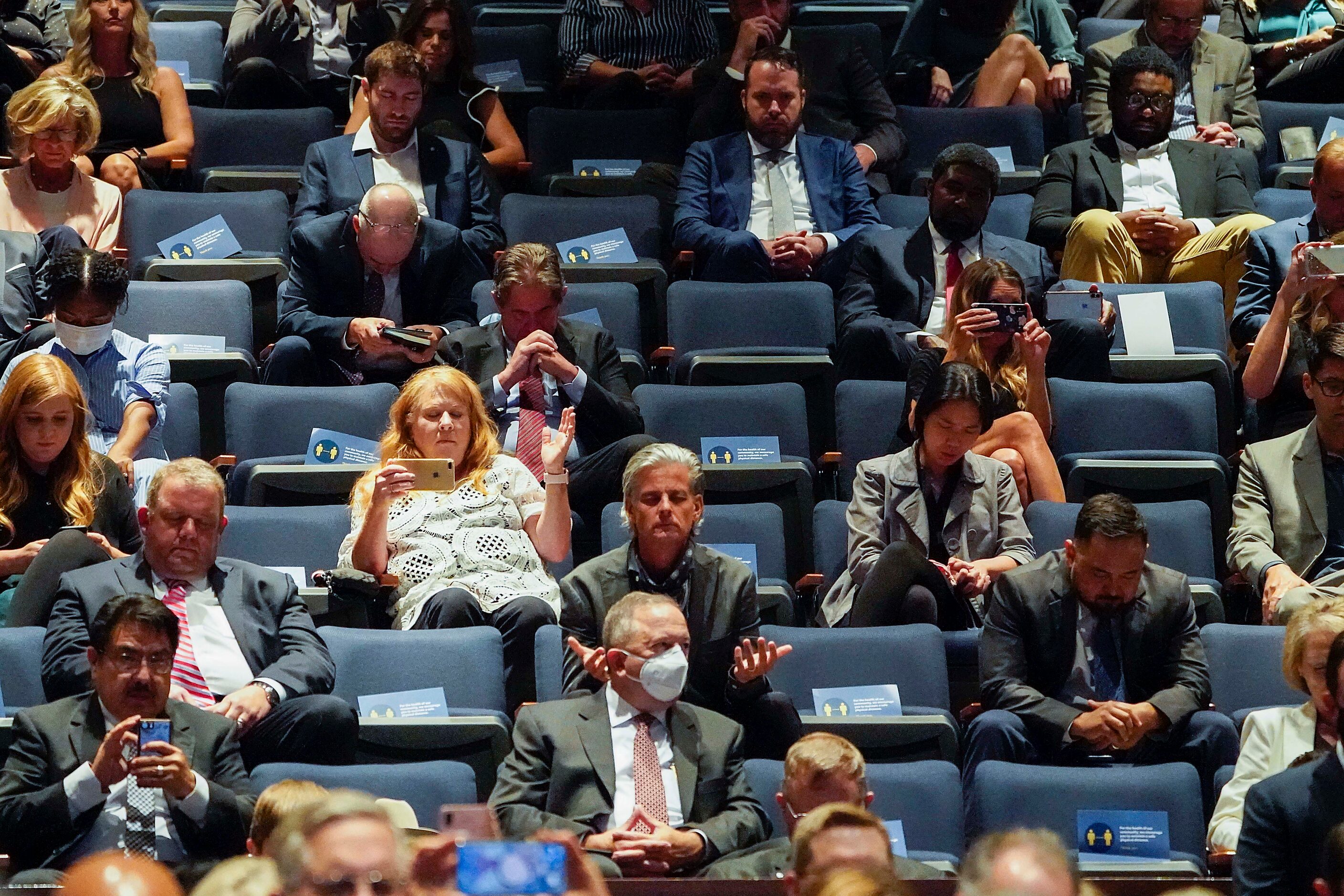 In a upper level of seating, social distancing cards are visible on unused chairs as people...