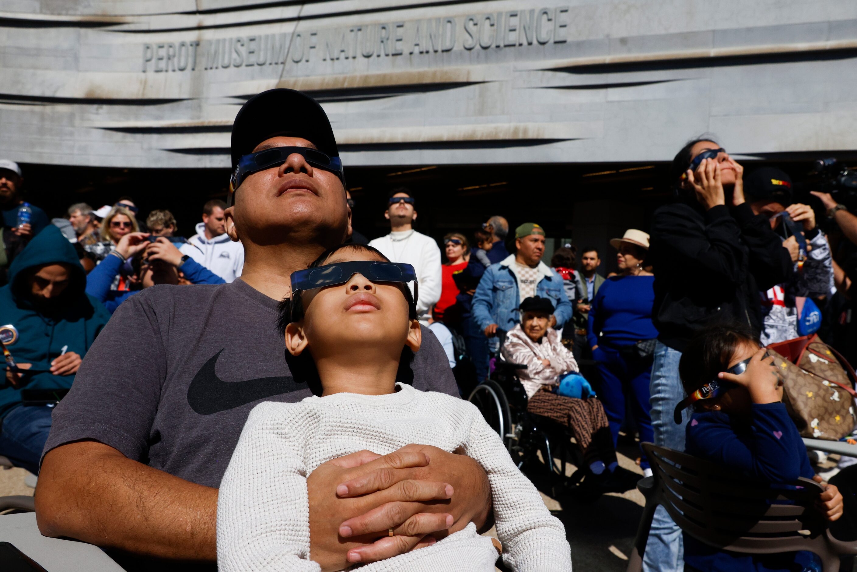 Juniper Panjaitan with his son Ferrel, 6, watch the peak of annular solar eclipse on...