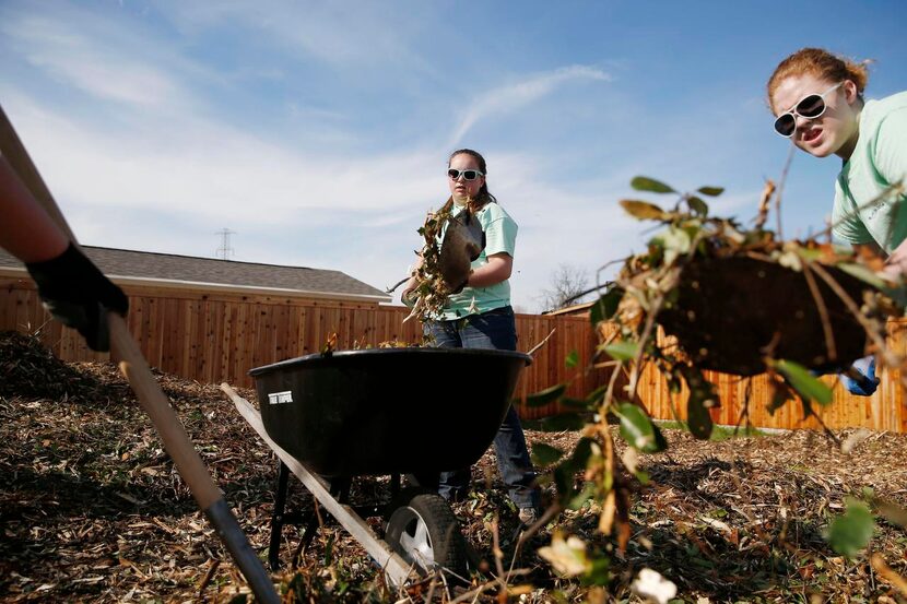 
Jennifer Moore (center), 16, and Lydia Brown, 15,move wood chips with other volunteers from...