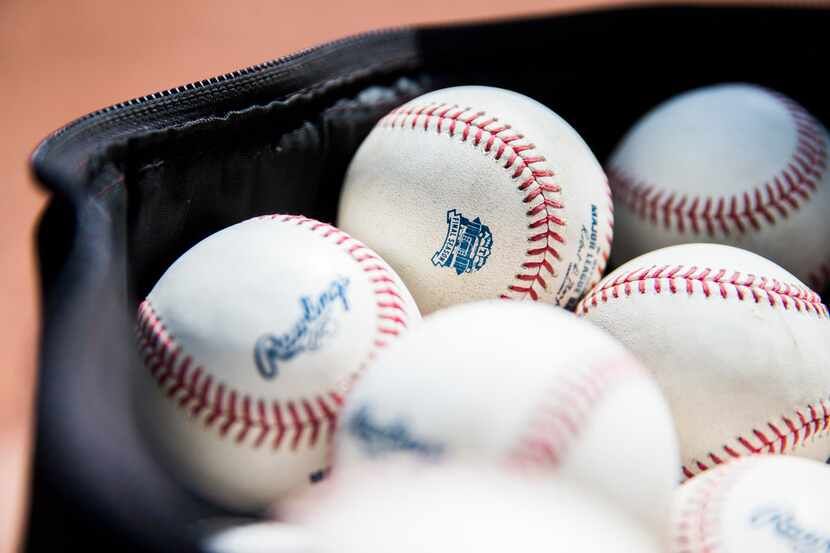 Baseballs stamped with a "final season" logo are piled in the dugout before an MLB game...