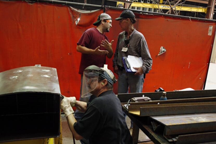 John Thompson (background left) and Allen Rowe confer as Ronnie Culver welds a lifting lug...