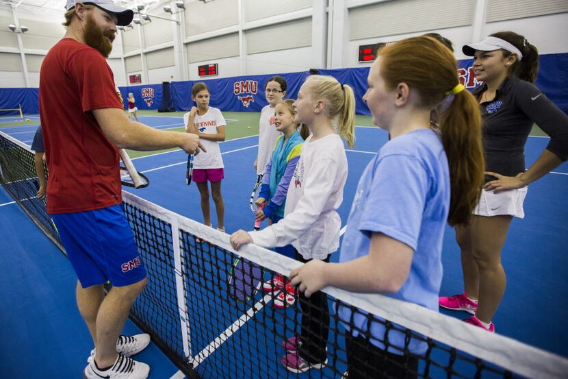 SMU Assistant Womens' Tennis Coach Mark Roberts, left, explains a game during a kids tennis...