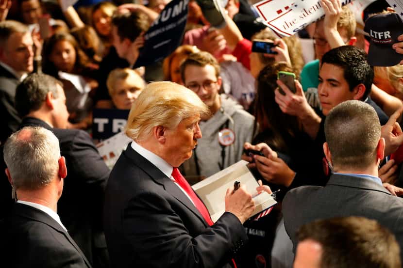  Republican presidential candidate Donald J. Trump signs a book for a supporter after a...