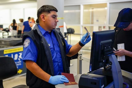 TSA transportation security officer Daniel Tays checks the passport of a traveler at a...