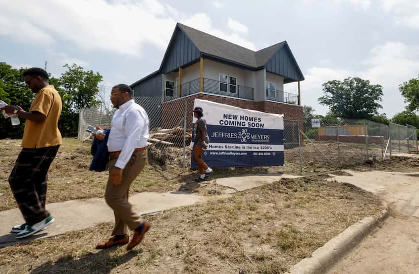 People pass by the first home built in an upcoming affordable housing development in South...