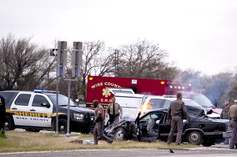 Law enforcement officers and emergency personnel work the scene of a crash and shootout in...