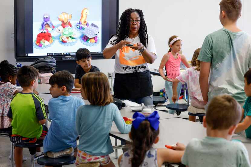 Art instructor Jo Patterson shows children the different pieces that will make up their art...
