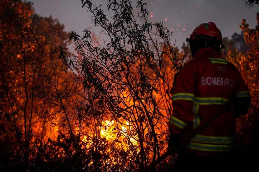 A firefighter combats a wildfire close to Monchique in the Portuguese Algarve, on August 8,...