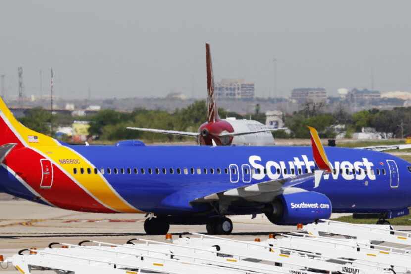 A Southwest Airlines airplane taxis to their gate as Virgin America airplane taxis to take...