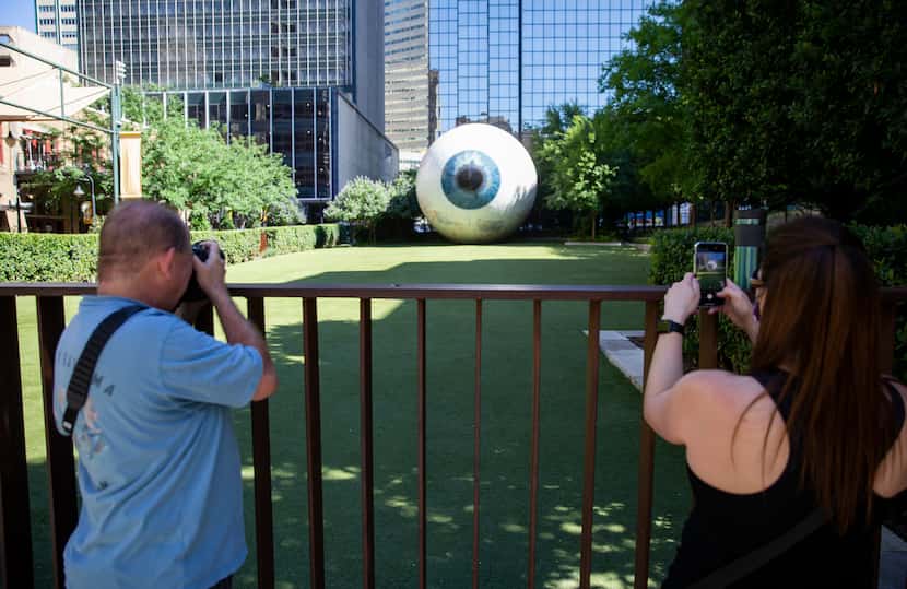 People take photos of the 'Eye' sculpture with graffiti covered up on Saturday morning, May...