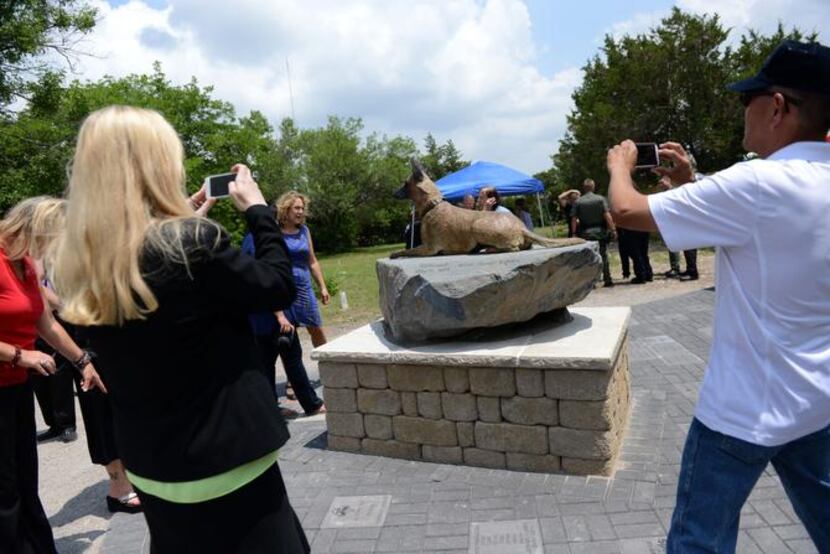
Attendees take photos of the War Dog memorial at Cedar Hill Pet Memorial Park. Plots are...