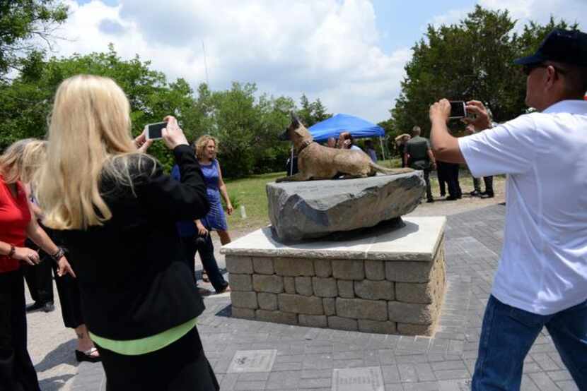 
Attendees take photos of the War Dog memorial at Cedar Hill Pet Memorial Park. Plots are...