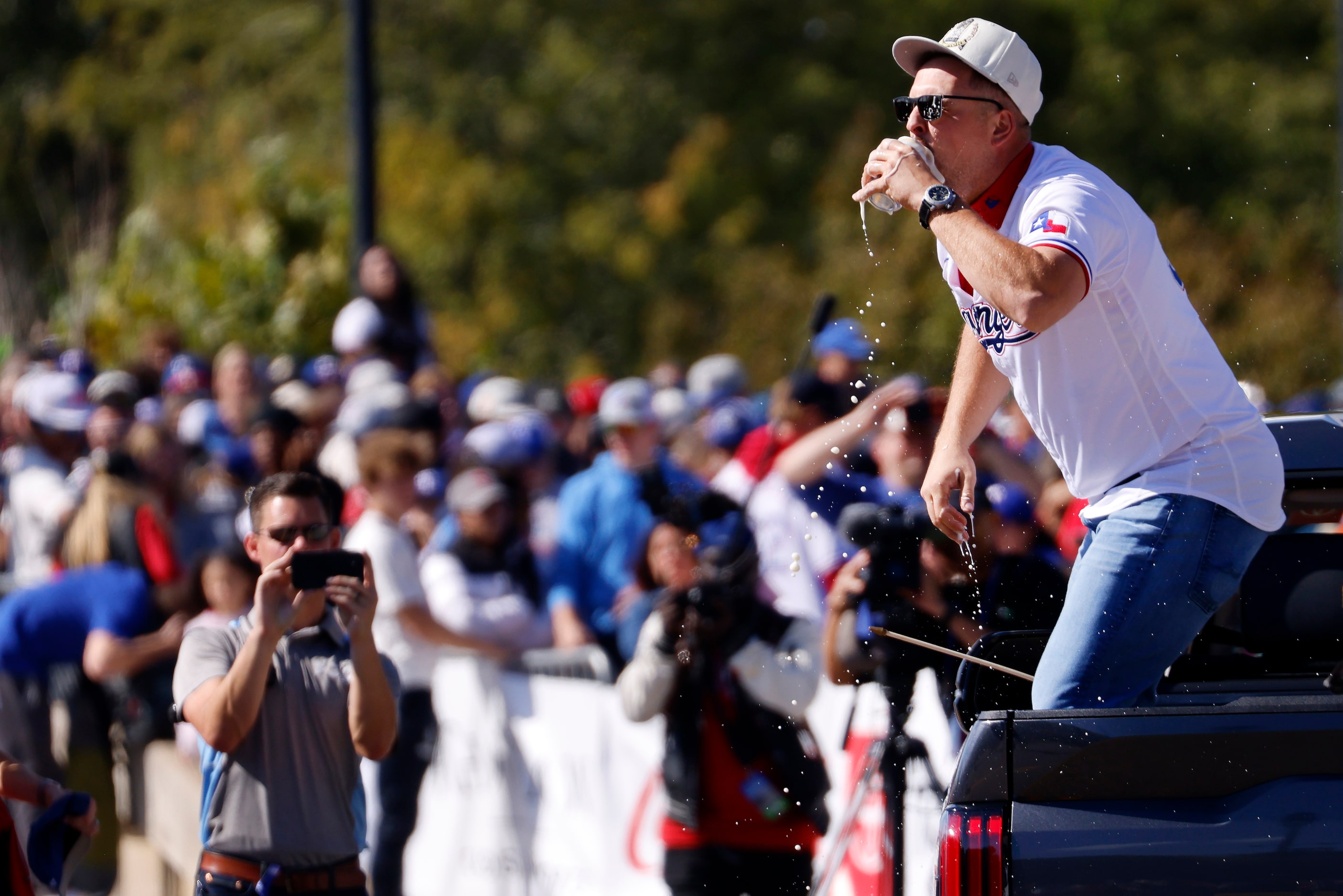 Texas Rangers first baseman Nathaniel Lowe chugs a beer for fans during the World Series...