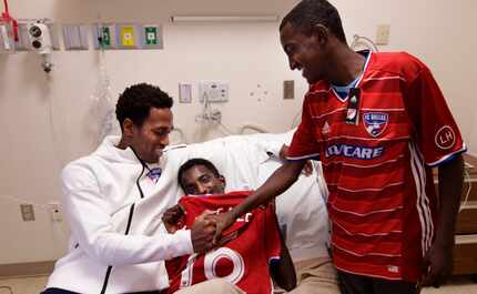 FC Dallas player Atiba Harris, left, visits with 16-yr-old Tamirat Bogale and 16-yr-old...