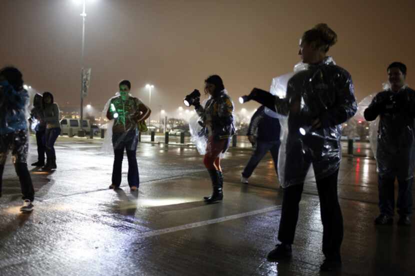 High school photography students shine flashlights on the pavement at Cowboys Stadium to...