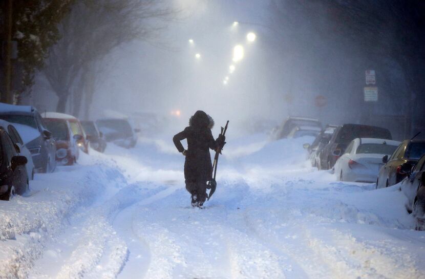 BOSTON, MA: A woman walks down snow-covered Maverick Street in the East Boston neighborhood...
