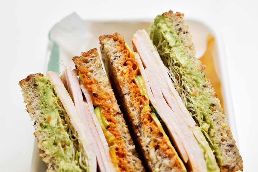 A turkey avocado sandwich layers roast turkey, avocado, harissa aioli, sprouts and...