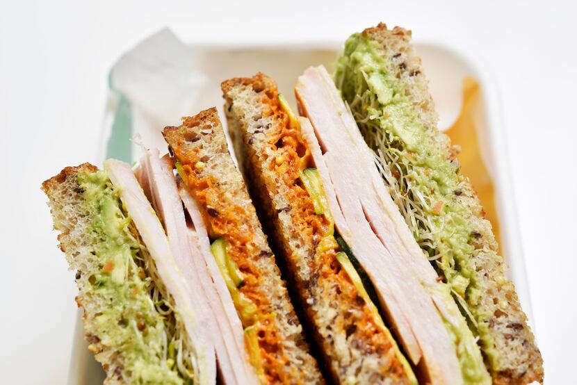 A turkey avocado sandwich layers roast turkey, avocado, harissa aioli, sprouts and...