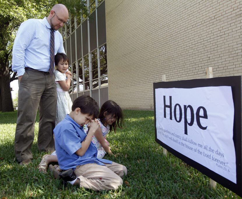 Tim Carpenter prays with his children Sydney, 5, Seth, 8, and Selah, 6, during a prayer walk...