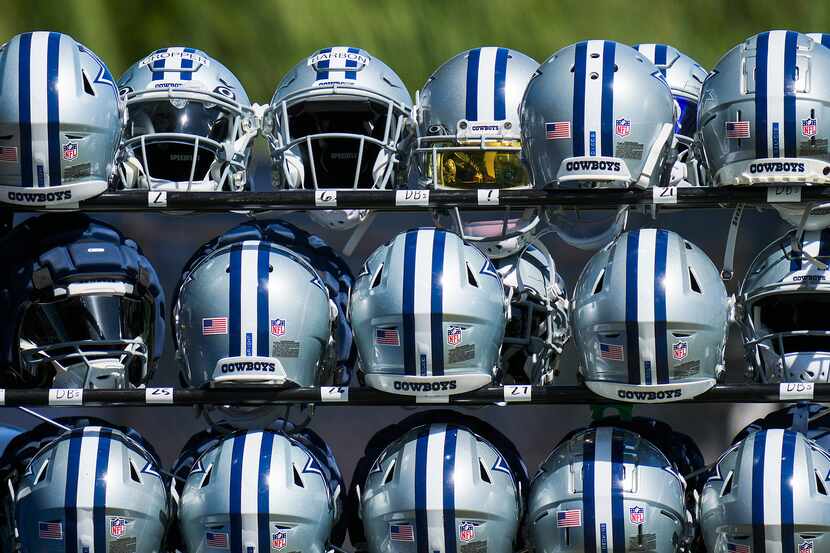 Dallas Cowboys helmets sit in a rack during a training camp walk-through on Wednesday, Aug....