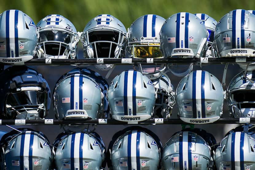 Dallas Cowboys helmets sit in a rack during a training camp walk-through on Wednesday, Aug....