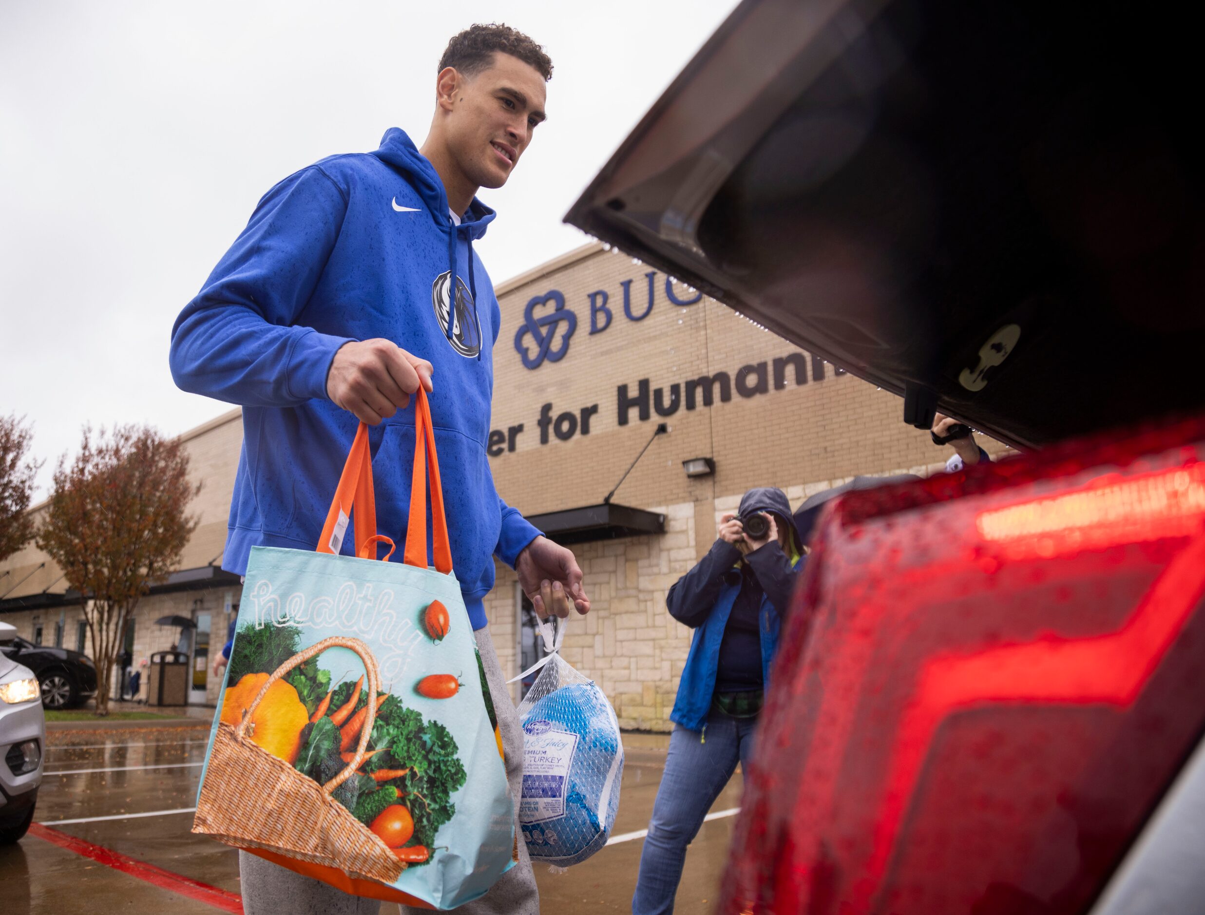 Dallas Mavericks center Dwight Powell (7) loads a car with a turkey and sides during the...