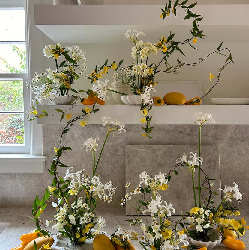 Organic floral installation with yellow and white flowers and orange peppers arranged in...