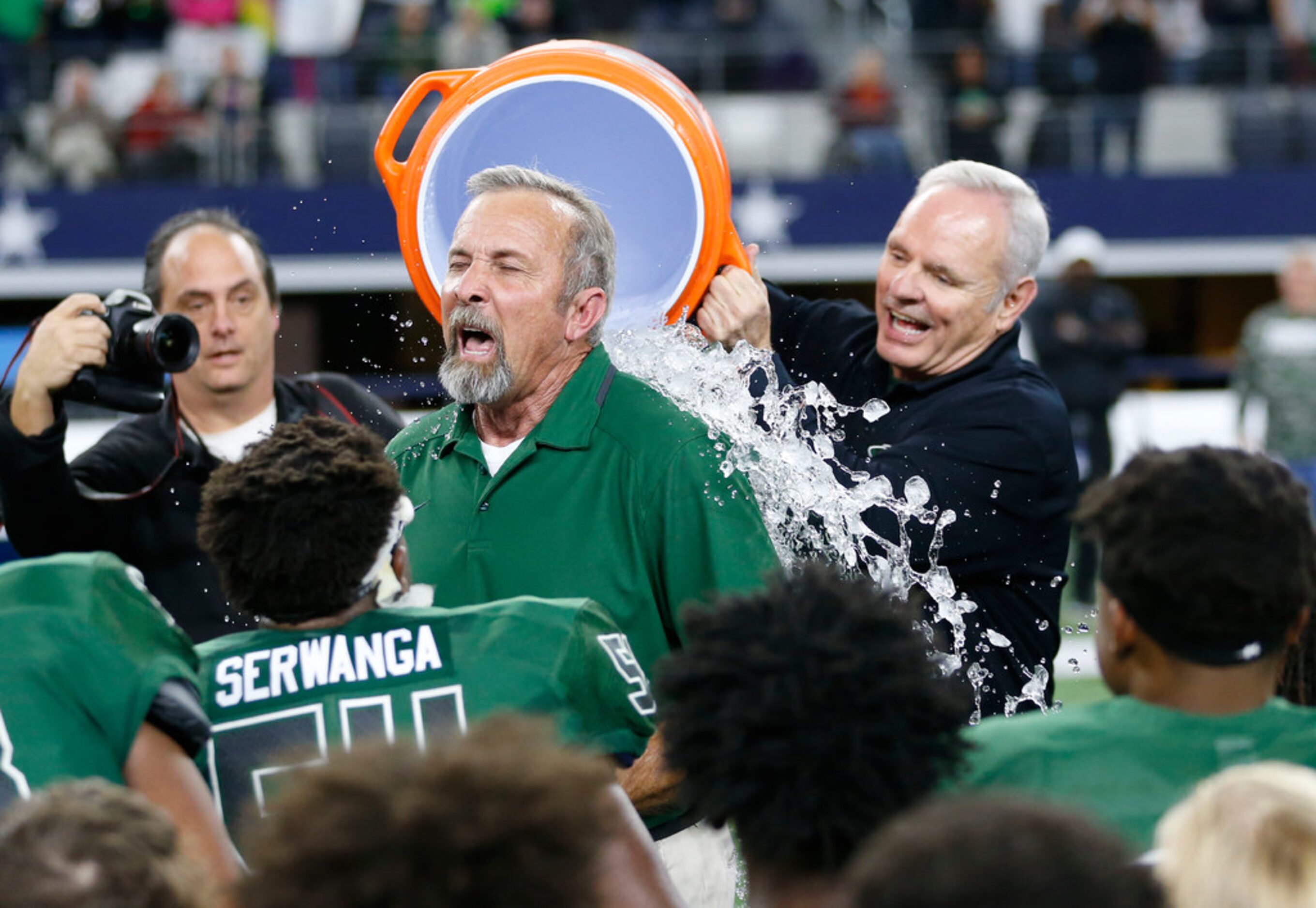 Kennedale's Richard Barrett gets doused with ice cold water as he talks to the team after...