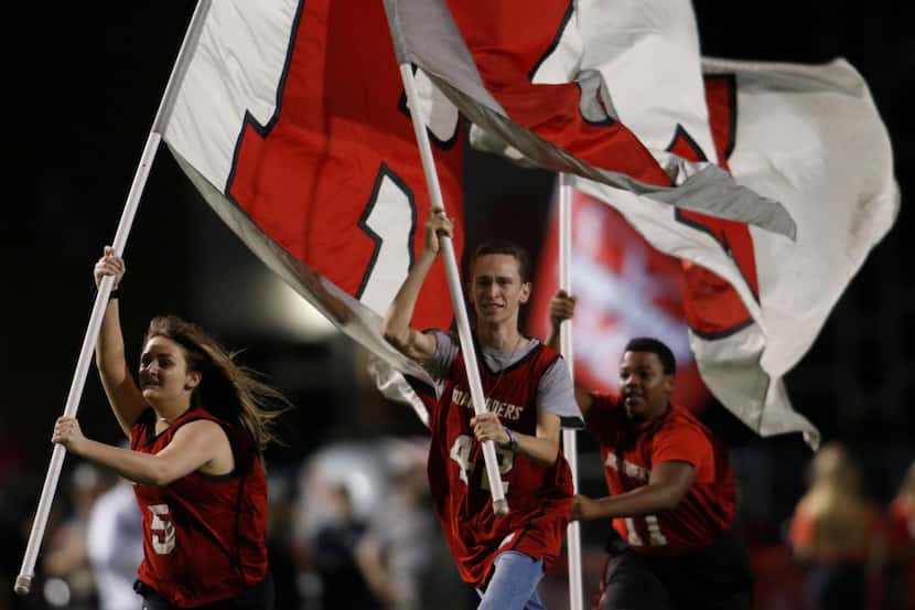 Members of the Flower Mound Marcus flag wavers squad sprint across the field following a...