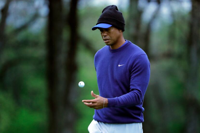 Tiger Woods flips his ball as he walks along the ninth green during a practice round for the...