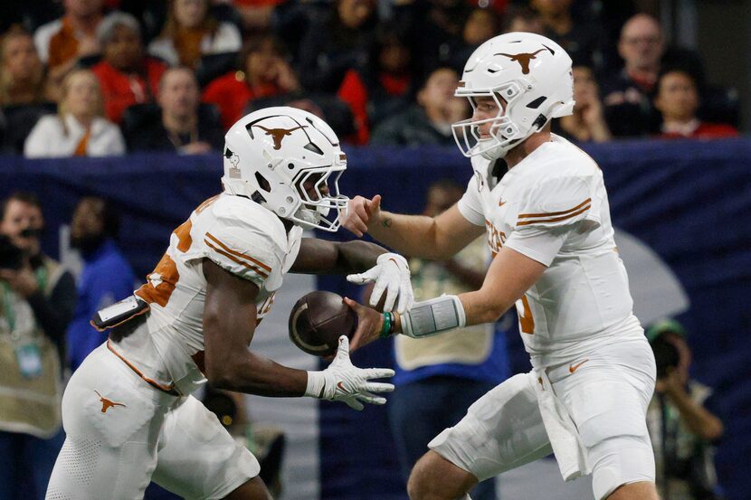 Texas quarterback Quinn Ewers (3), right, hands off to Texas running back Quintrevion Wisner...